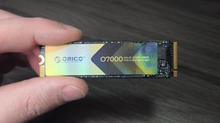 एक हाथ में Orico O7000 SSD है